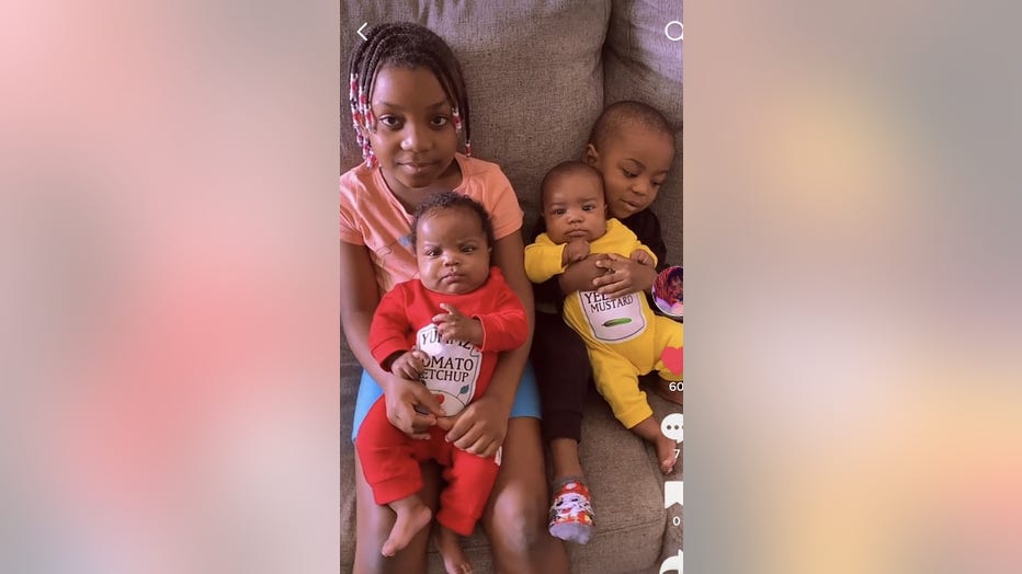 A family of 4 young siblings sit on the couch.
