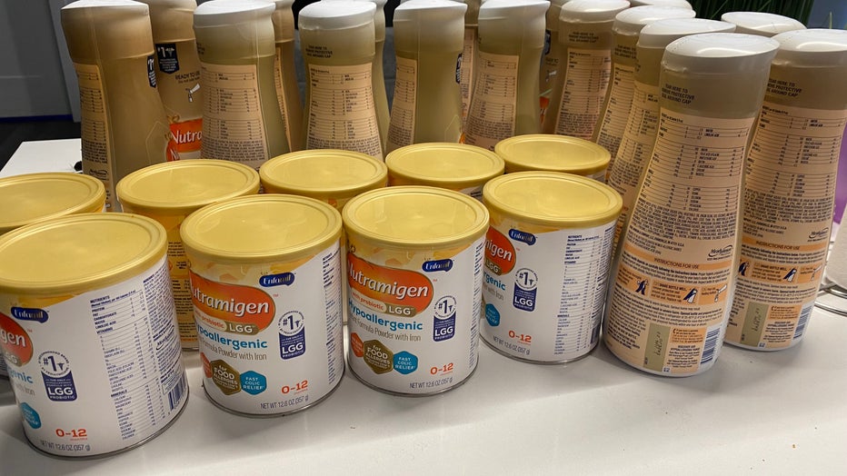 Cans and bottles of baby formula line a kitchen counter.