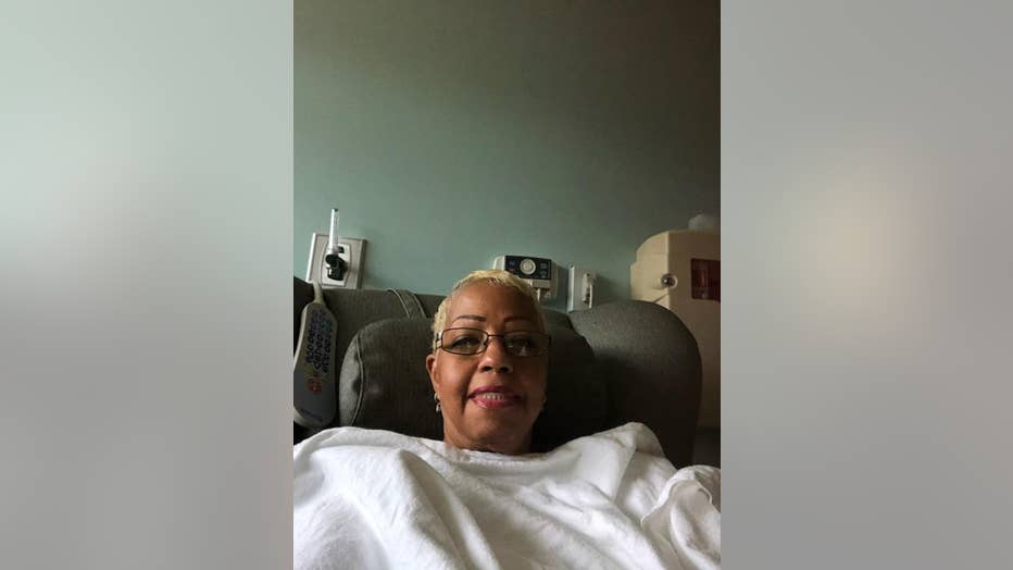 Woman covered in a blanket sits in a chemotherapy infusion chair.