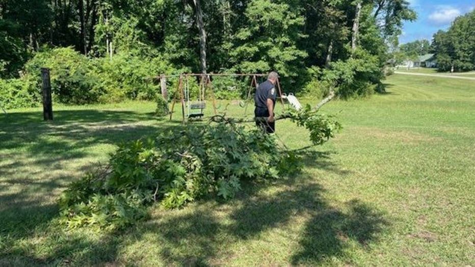 A Henry County police officer helps clear a fallen branch from the yard of Florence Martin, who turns 107 this week.