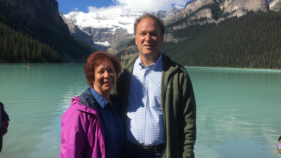 Man and woman pose in front of a beautiful mountain lake