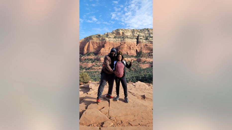 Man hugs his pregnant wife's belly on a hiking trip