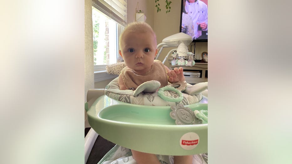 Baby in jumpy chair looks at the camera.