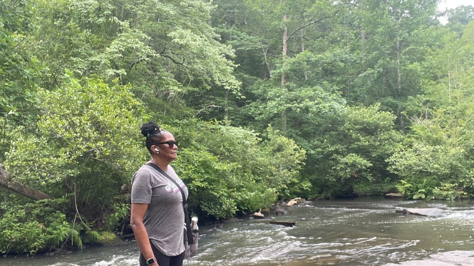 Woman stands alongside a river