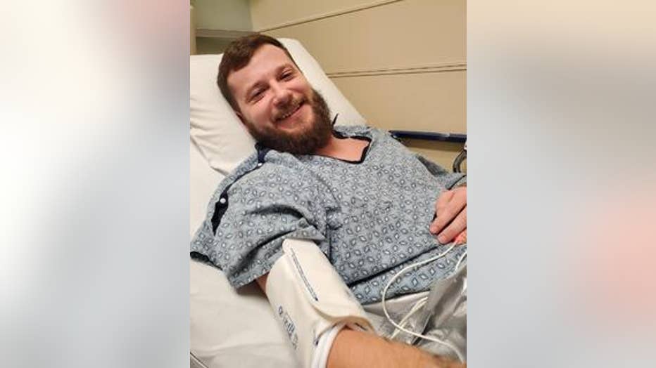 Man in hospital gown smiles from gurney