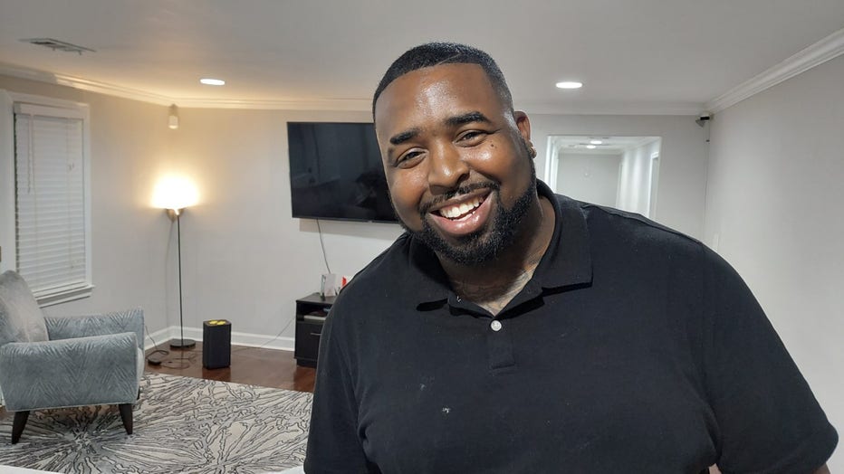 African American man in his thirties smiles in his Atlanta living room.