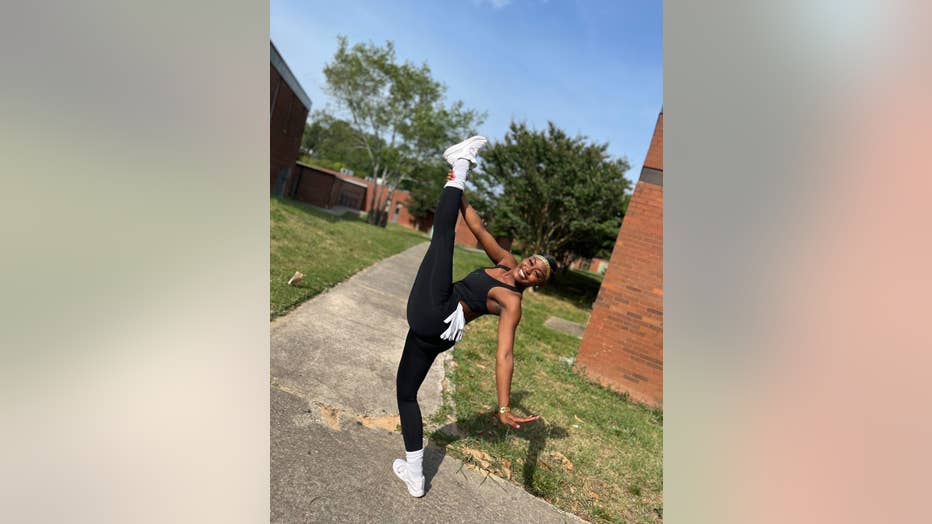 Teen in dance leotard poses with her leg kicked high in the air.