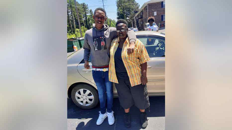 Mother and son hug as they stand together in a parking lot