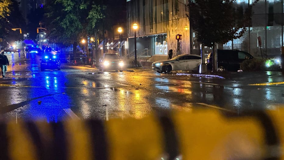 A crime scene investigators take pictures of a white Mercedes Benz and the surrounding road after police say a plainclothes man was forced to open fire during a road rage incident on West Peachtree Road near 16th Street in midtown Atlanta on Oct. 25, 2022.