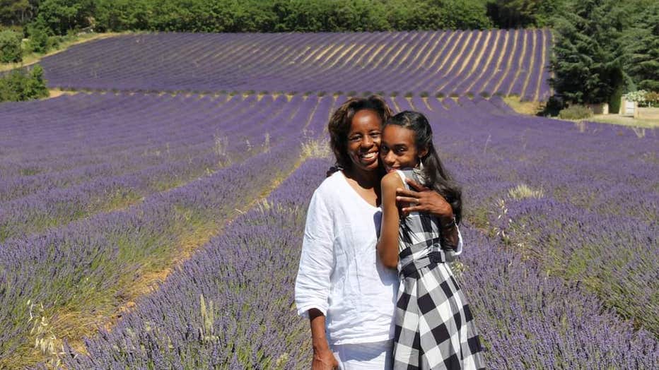 Mother and daughter hug in a field of lavender.