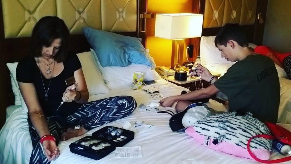 Mother and son sit on bed giving themselves injections of medication