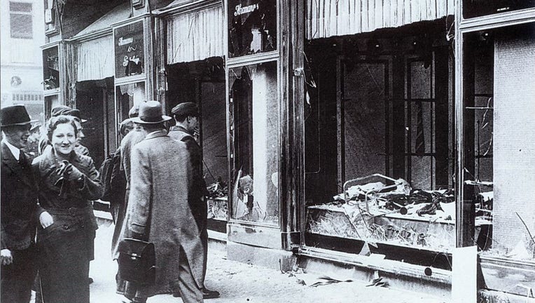 Pedestrians glance at the broken windows