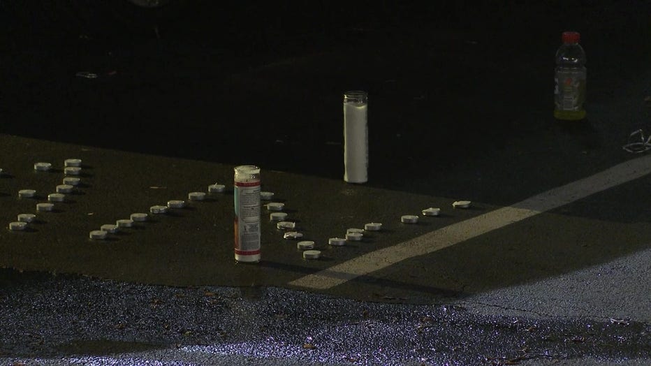 Candles line the parking lot of a Flat Shoals Road apartment complex during a vigil that was interrupted by gunfire on Nov. 27, 2022.
