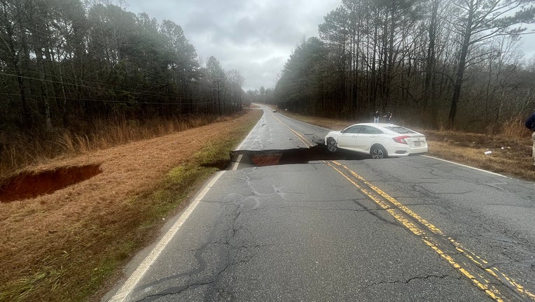 A car gets stuck after a fissure opens up in the middle of a roadway in Clarke County due to flooding on Jan. 4, 2023.