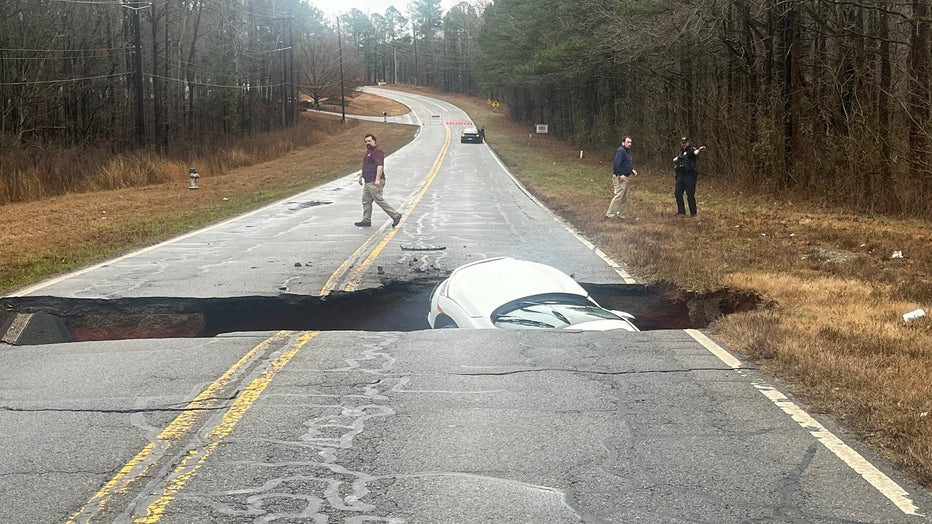 A car that got stuck in a newly opened fissure in the middle of a Clarke County roadway falls in the schism widens on Jan. 4, 2023.