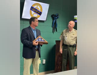 Rep. Austin Scott hands Crisp County Sheriff Hancock a flag flown over the U.S. Capitol to honor fallen Deputy Tyee Brown on Aug. 8, 2023.
