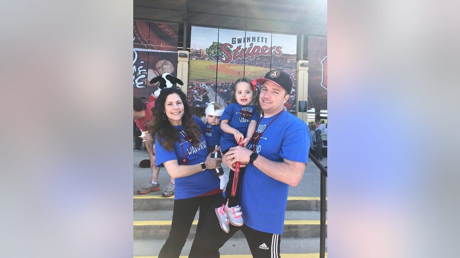 A couple poses holding their two young children, who appear to be about 3 and 1.