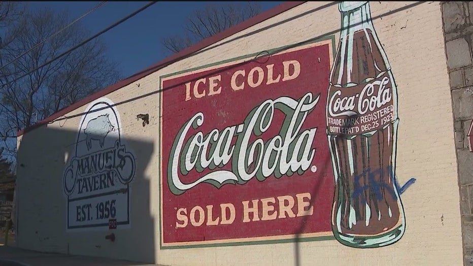 Graffiti was sprayed over the historic Coca-Cola mural outside of Manual’s Tavern in Atlanta as part of vandalism at the venue ahead of a political appearance by Mayor Andre Dickens.