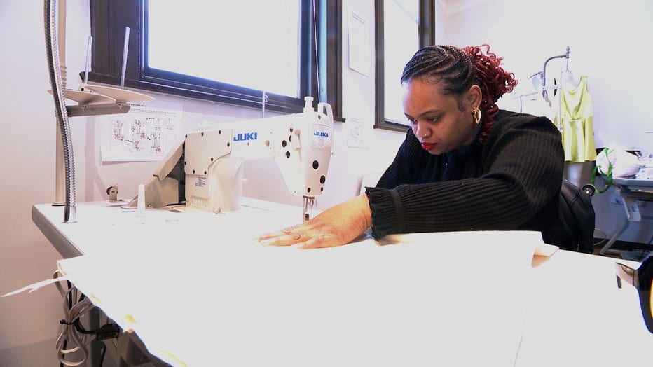 Young Black woman concentrates as she sews a design on her sewing machine.