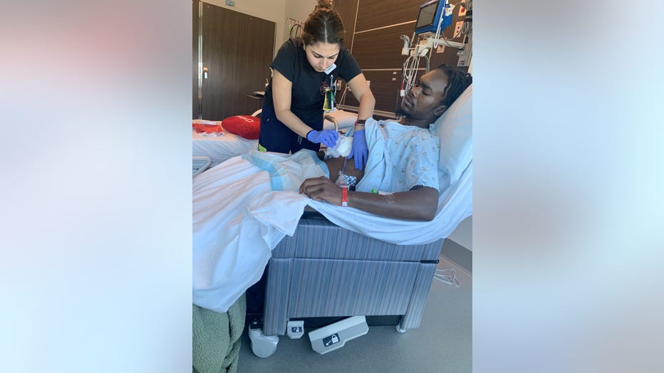 Evan Holyfield, 26, sits in a hospital chair as his wound dressing is changed.