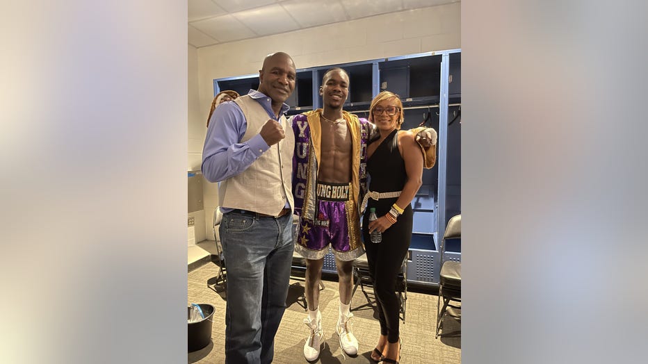 Evan Holyfield, 26, poses between his parents