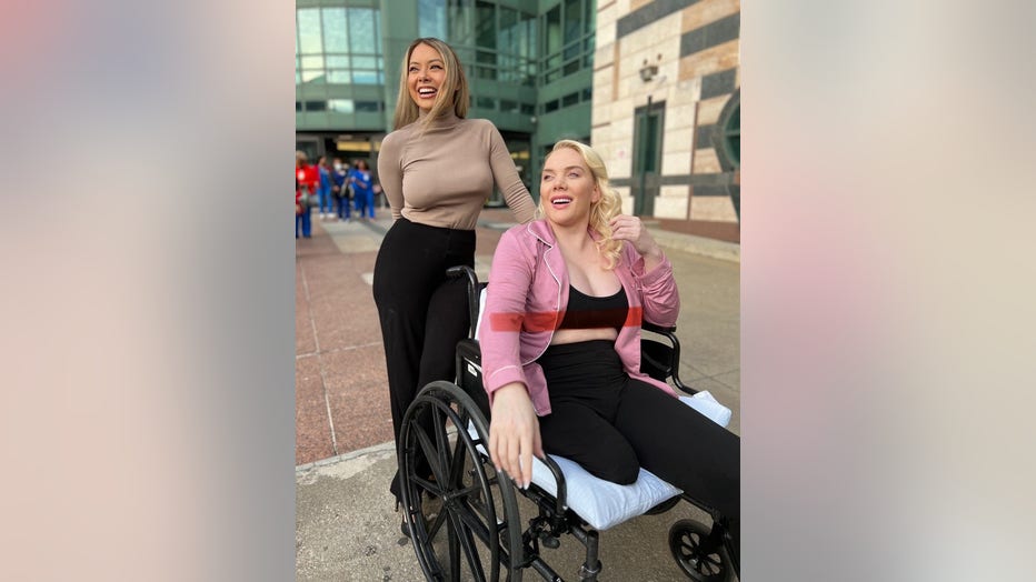 A young woman in a wheelchair smiles as she leaves the hospital