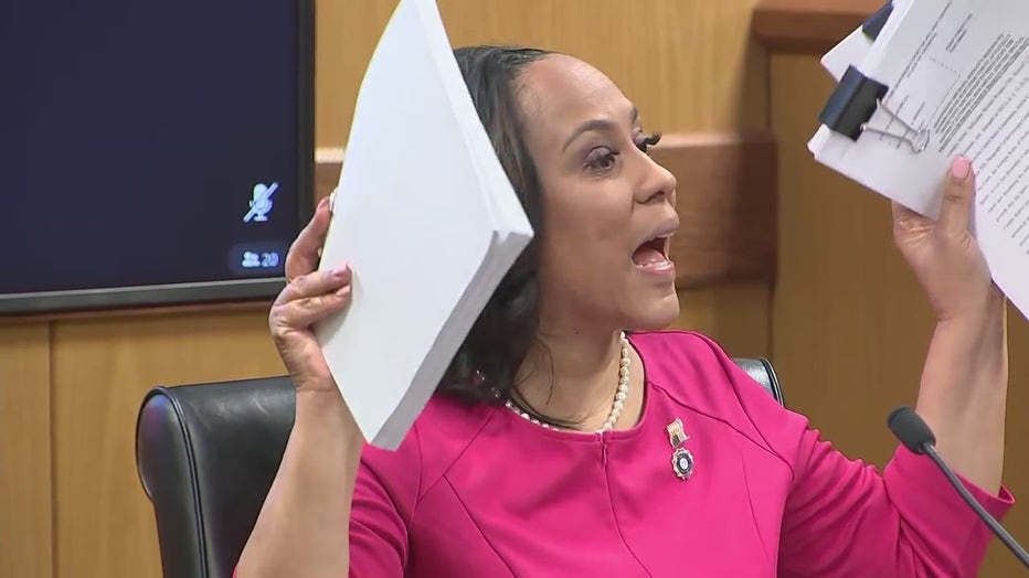 Fulton County DA Fani WIllis holds up documents while on the witness stand accusing defense attorneys of lying during her disqualification hearing in the Trump Georgia election interference case on Feb. 15, 2024