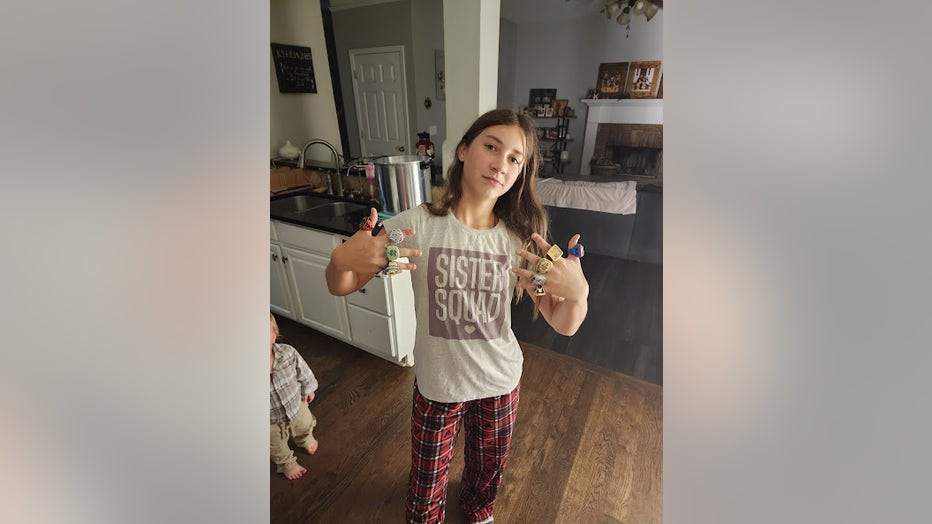 13-year-old girl wearing a t-shirt that says "Sister Squad" shows of championship rings on most of her fingers