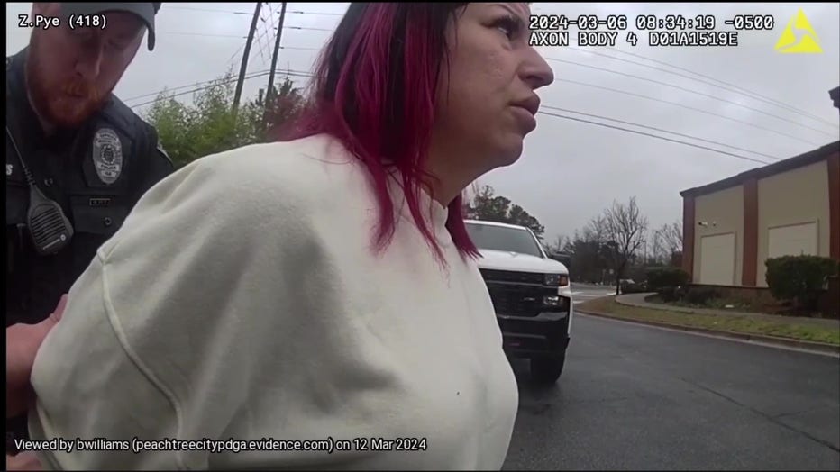 Erika Rylant, 40, of Coweta County is placed in handcuffs outside Cool Beans located along Highway 54 in Peachtree City on March 6, 2024.