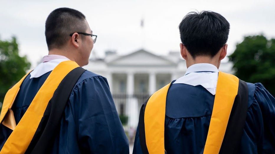 FILE - Students from George Washington University wear their graduation gowns outside of the White House in Washington, DC, on May 18, 2022. (Photo by STEFANI REYNOLDS/AFP via Getty Images)