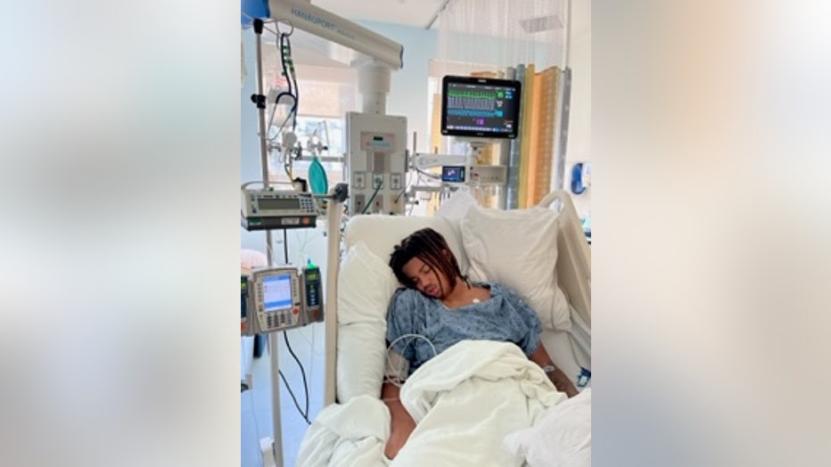 A young man sleeps while sitting upright in a hospital bed.