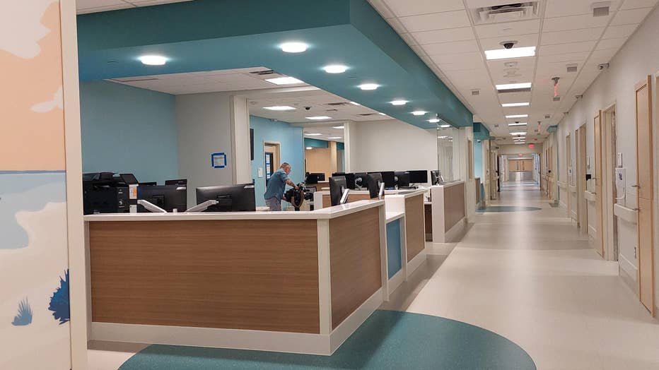 A hallway of a new emergency department, which staff desks on one side and treatment rooms on the other