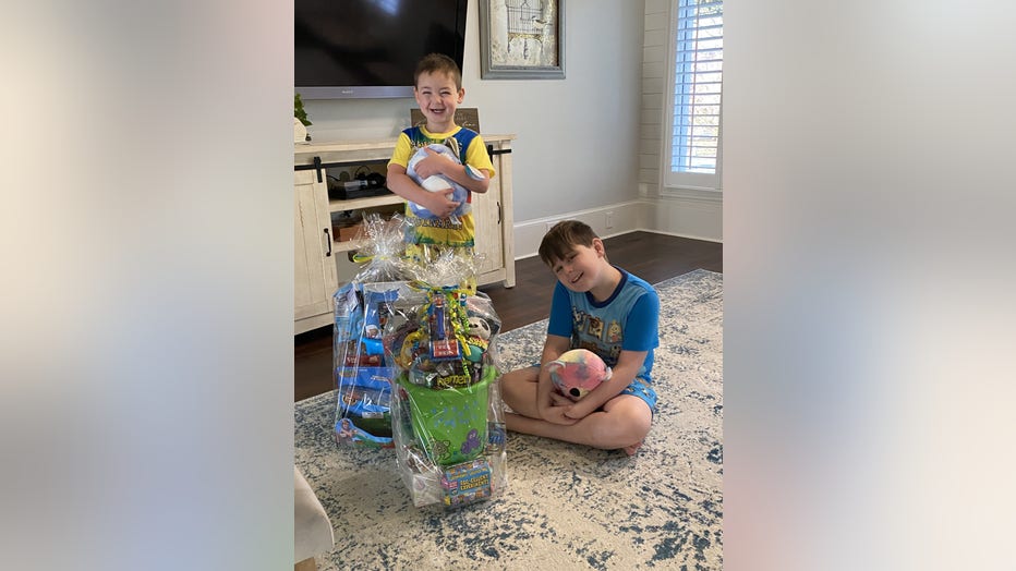 Two brothers pose with gifts in their home.