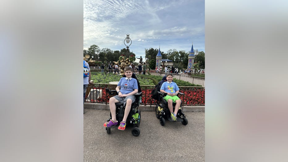 Two brothers sit in side-by-side power wheelchairs at Disney World.