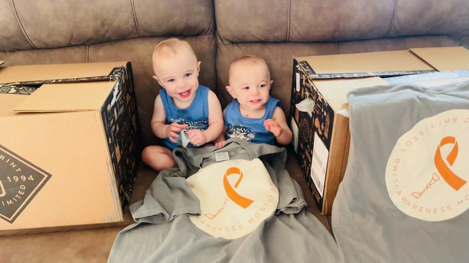 Blond twin boys sit on the floor in front of their couch.