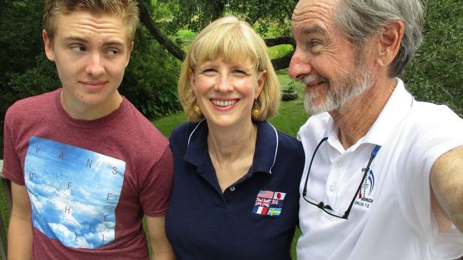 A teenage boy poses in a photo with his mother and stepfather, who appears to be taking a selfie.