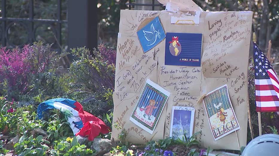 Tributes, mementos, flowers and even peanuts line the sign of the Carter Center, found by former President Jimmy Carter and his wife, Rosalynn, on Jan. 3, 2025.