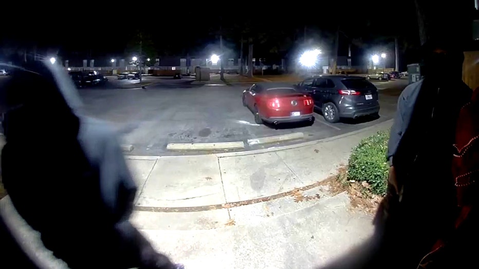 Two masked individuals stand outside an apartment door, with one appearing to hold a gun, just before shots were fired into a southwest Atlanta unit. The video was captured at a Continental Colony Parkway complex on December 10, 2025.