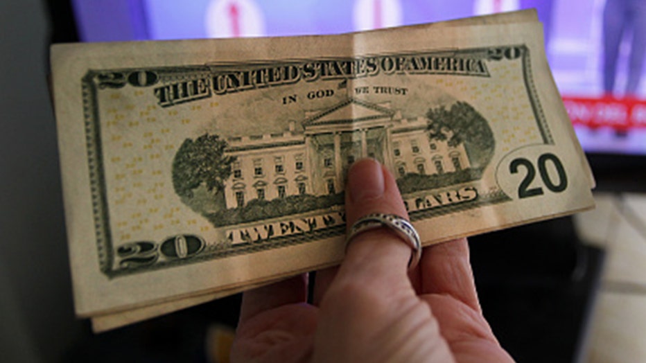 FILE: A woman holds up a stack of United States Dollar (USD) bills.