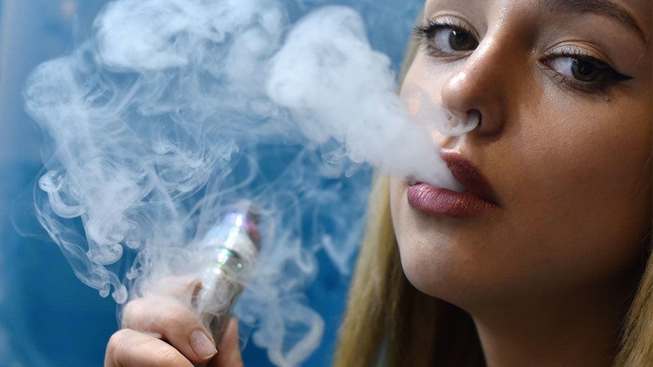 A promoter puffs from an e-cigarette while working at a stand during Vape Jam 2019.
