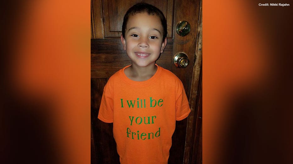 Blake, 6, is shown wearing his custom T-shirt that is orange with bright green letters that say 