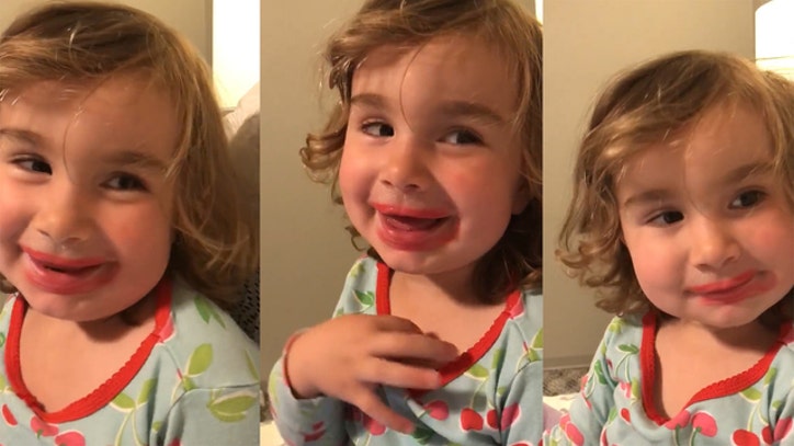 Little girl smiling, wearing lipstick