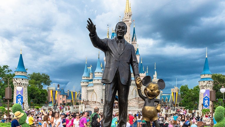 Walt Disney and Mickey Mouse statue inside of the Magic Kingdom theme park . The Cinderella castle can be seen in the background.
