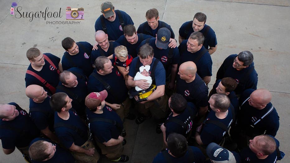 Brett Grace's grandfather, also a firefighter, holds her at a recent photo shoot with her father's fellow firefighters. 