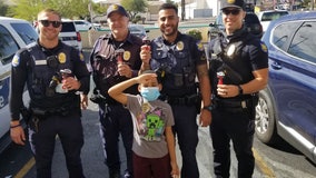 Boy gifts officers candy with toy police cars on top to show appreciation