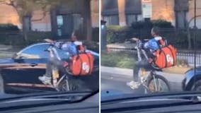 Grubhub delivery guy riding bike with one wheel getting attention across DC