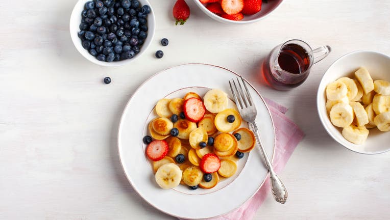 Trendy food - pancake cereal. Home breakfast with tiny pancakes and berries. View from above.