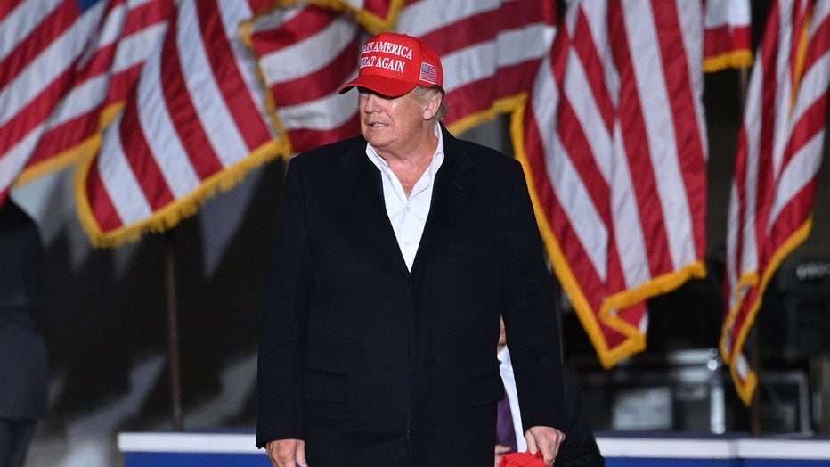 Former US President Donald Trump holds MAGA hats for his supporters, as he arrives to speak at a rally at the Canyon Moon Ranch festival grounds in Florence, Arizona, southeast of Phoenix, on January 15, 2022.(Photo by ROBYN BECK/AFP via Getty Images)