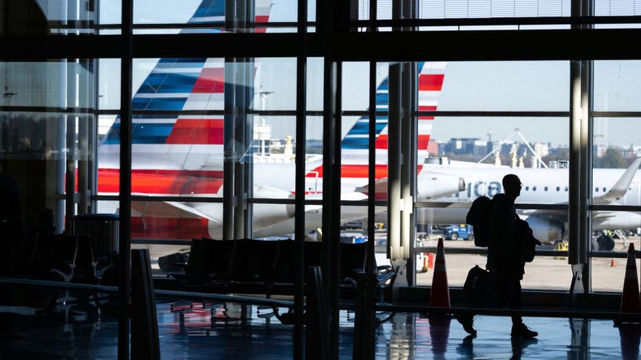 American Airlines airplanes are seen past a traveler walking through Ronald Reagan Washington National Airport in Arlington, Virginia, on Nov. 22, 2022. (Photo by SAUL LOEB/AFP via Getty Images)