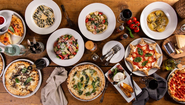 Big dinner table with italian food, pizzas and pastas